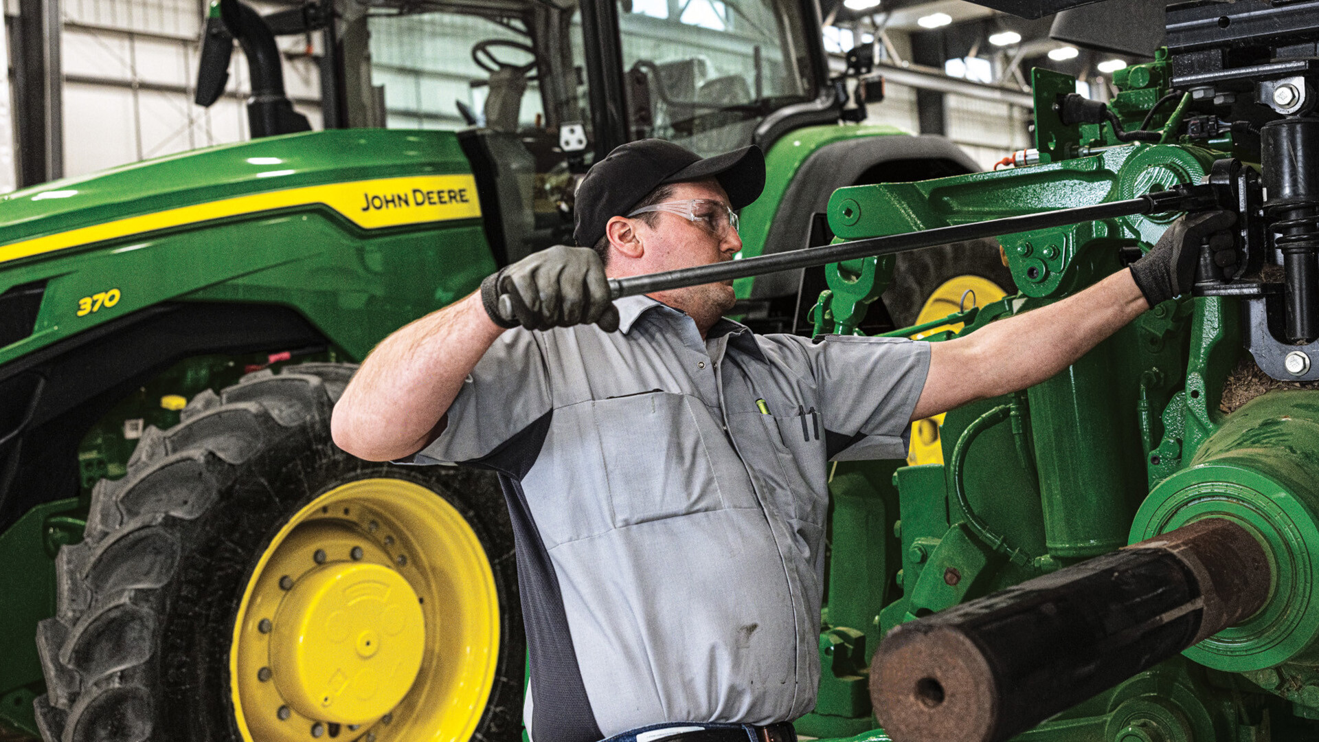 A Koenig technician servicing a John Deere 8R row crop tractor in the shop