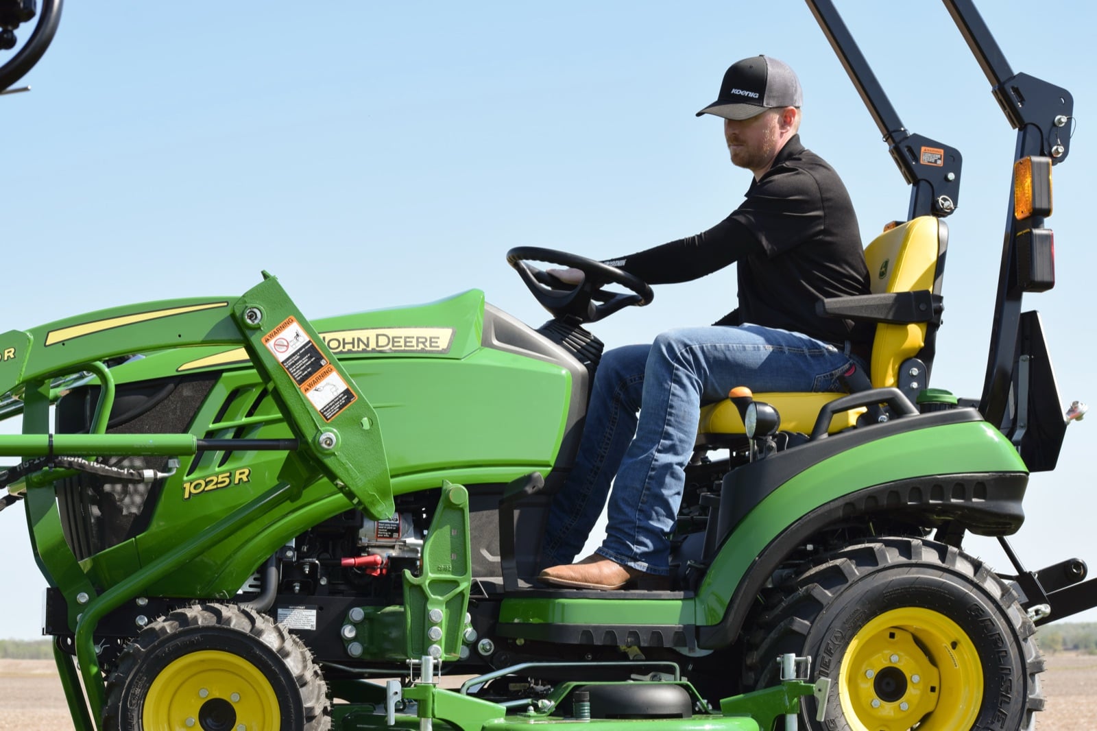 An operator driving a John Deere 1025R with a 120R loader