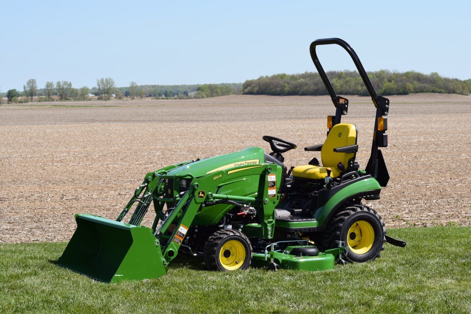 John Deere 2025R with a loader and mower deck beside a field