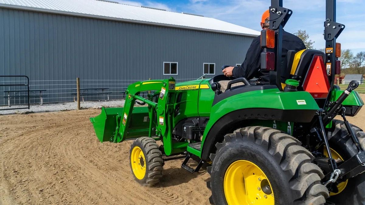 A John Deere 2 Family tractor with a loader in a dirt lot