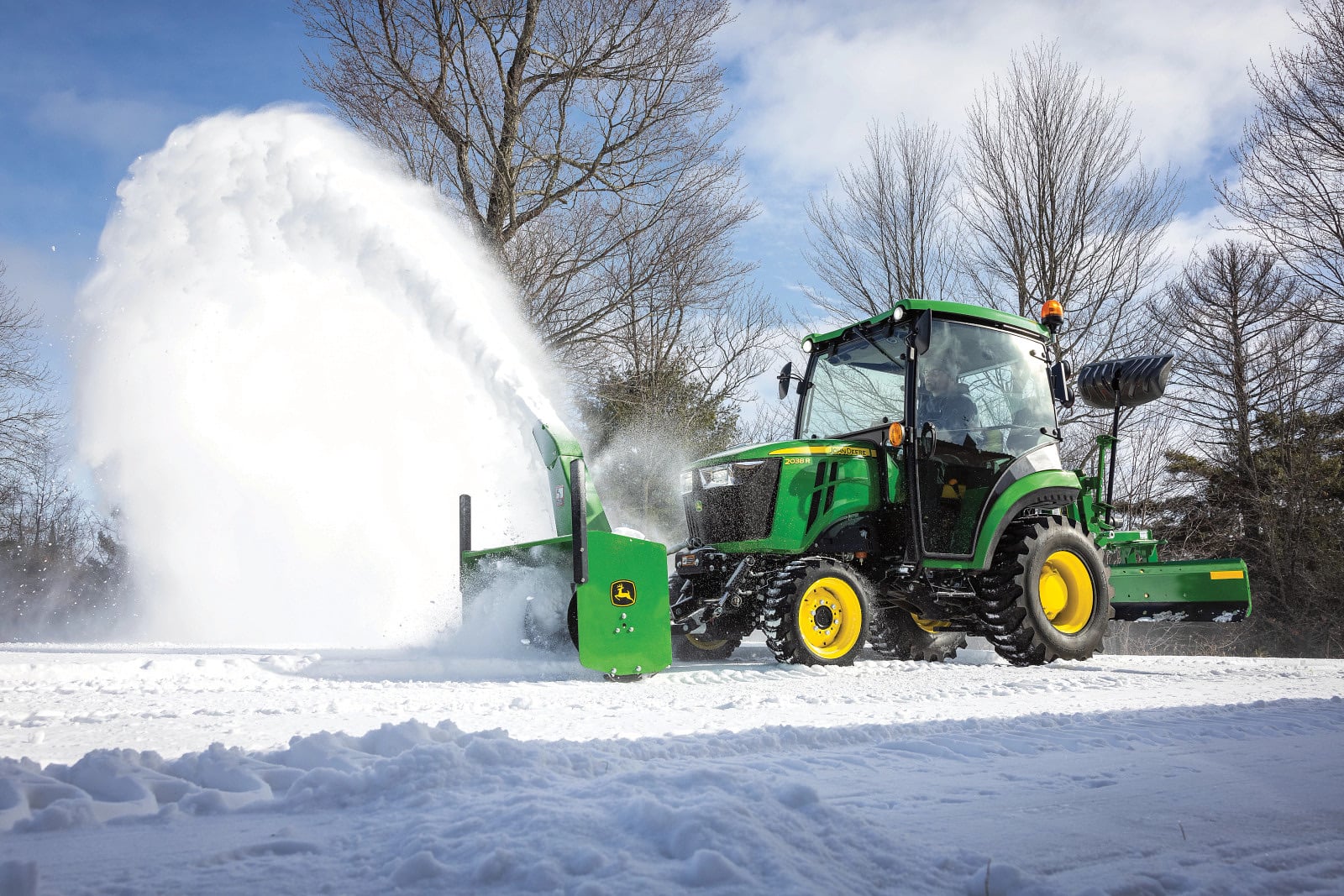A John Deere 2038R cab tractor clearing snow