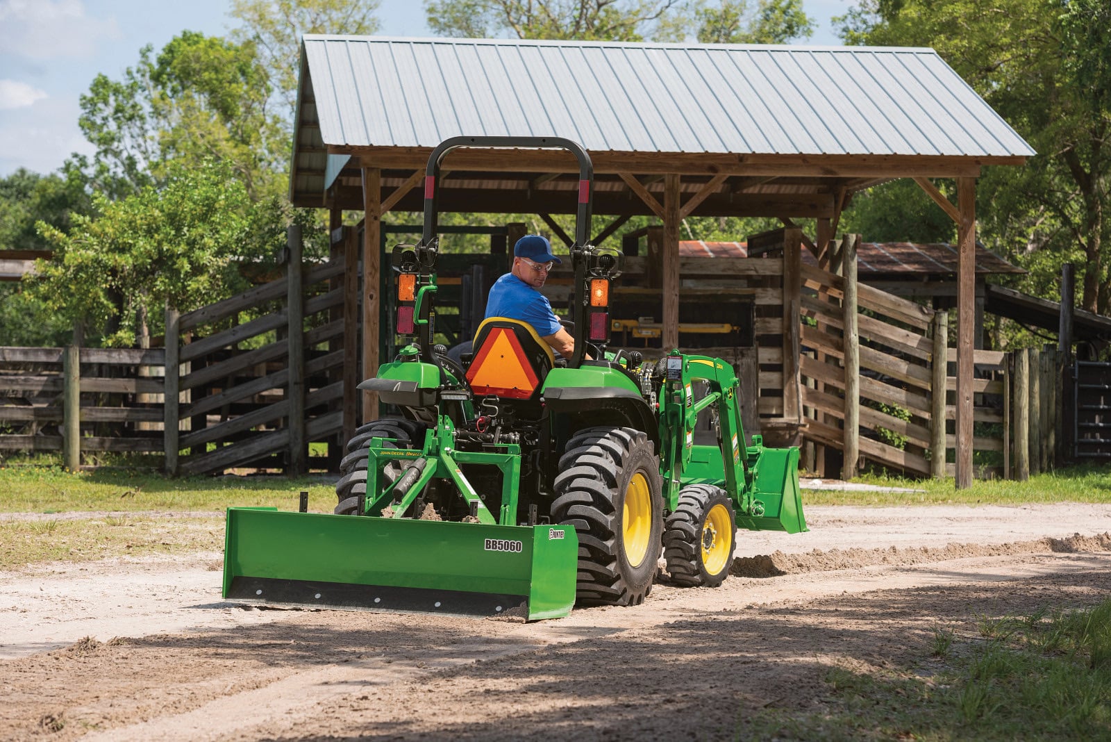 A John Deere 2032R with a loader by a shed