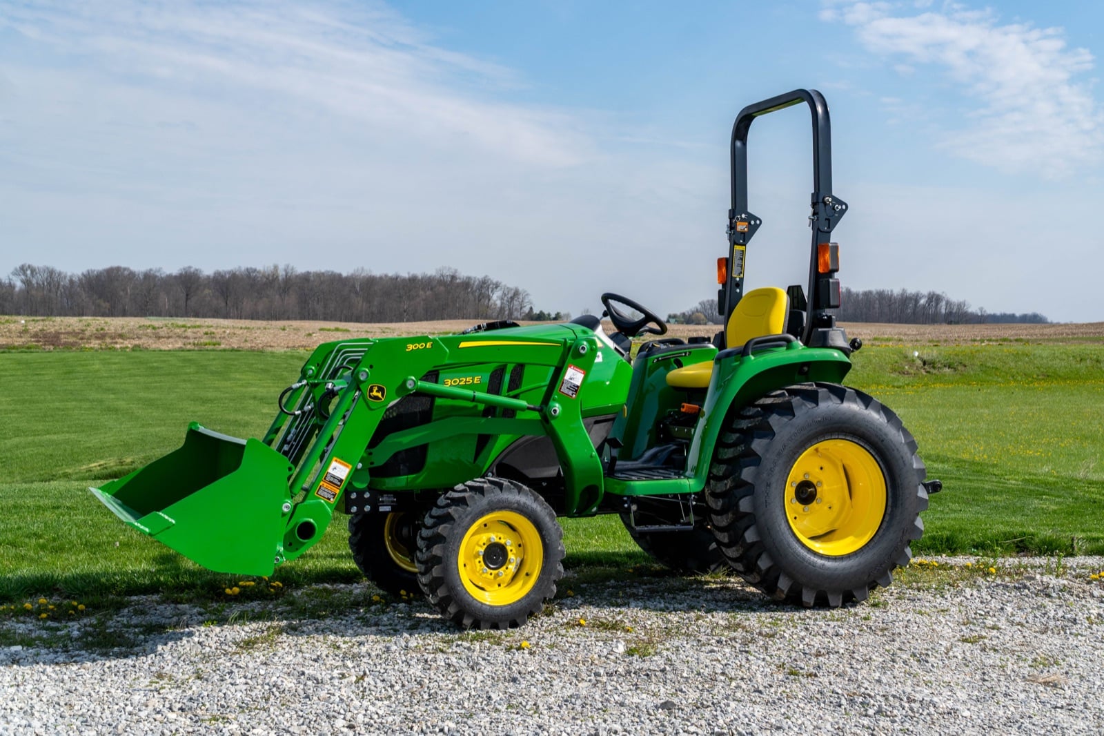 John Deere 3025E with a 300E loader by a field