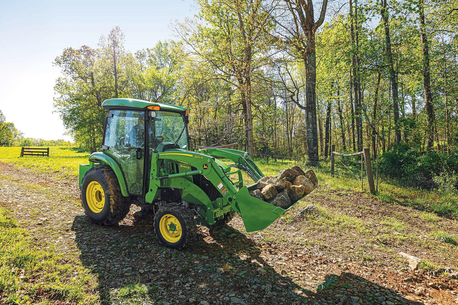 A John Deere 3046R hauling rock