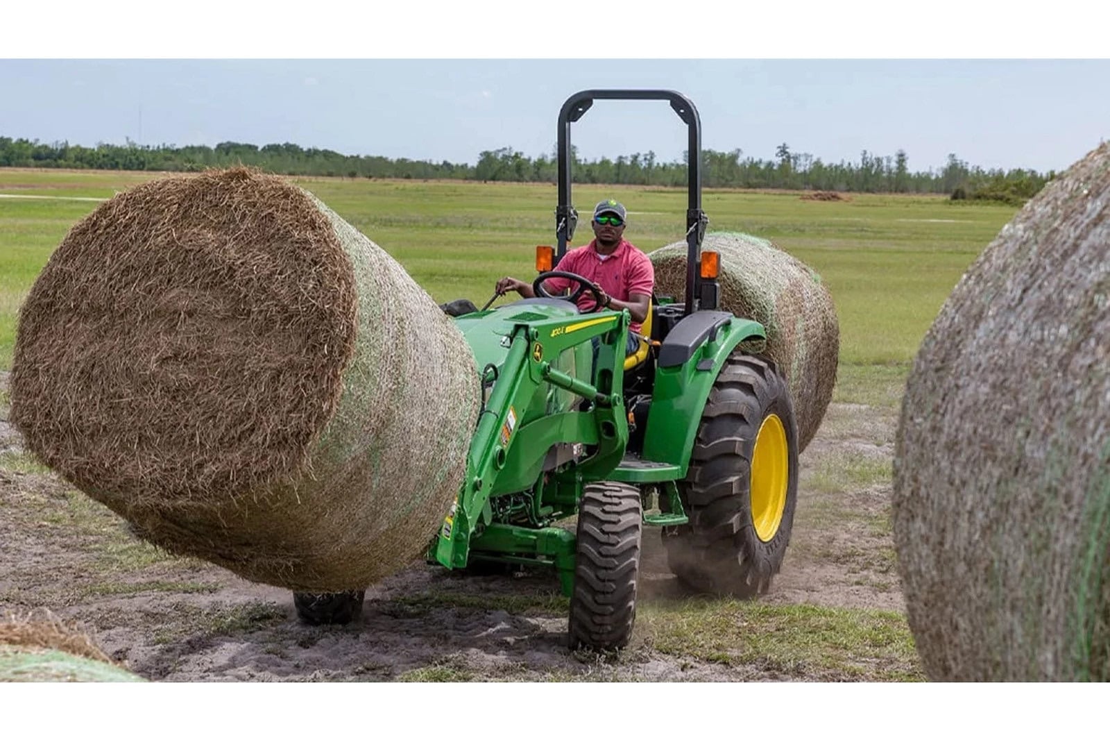 A John Deere 4044M moving round bales