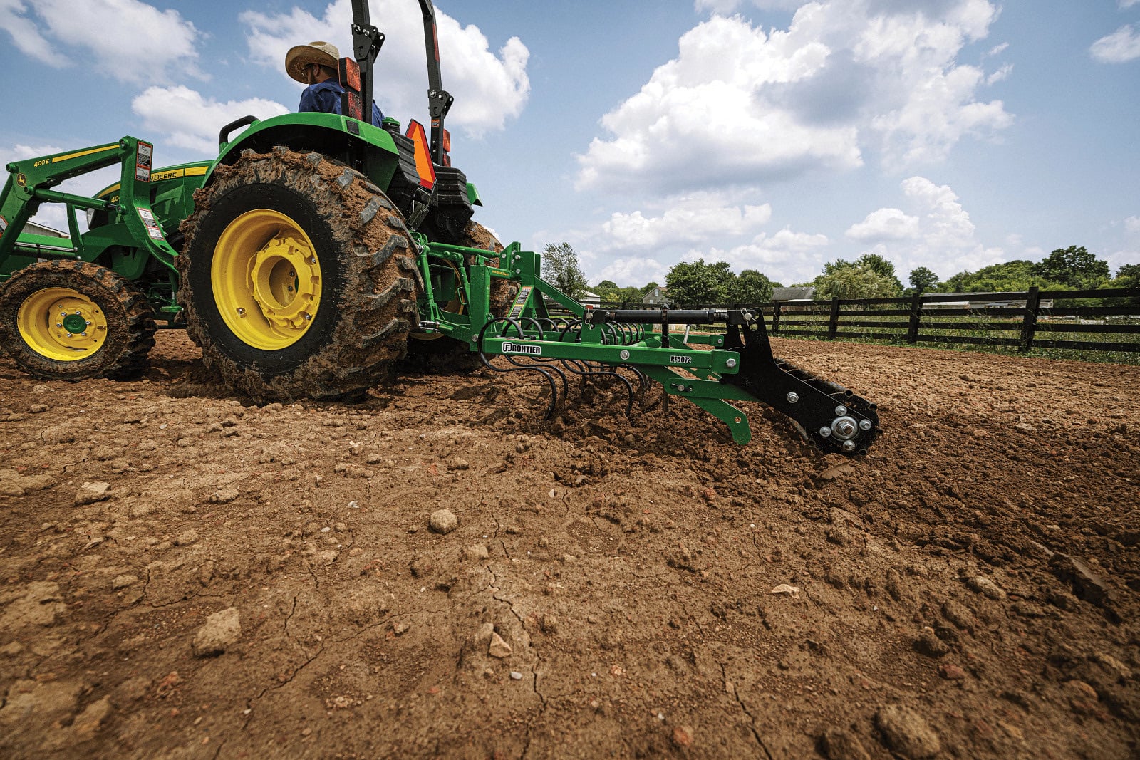 A John Deere 4044M working ground with a rear implement